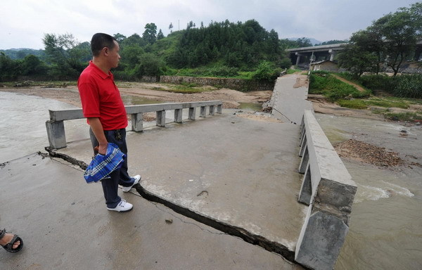 A pedestrian looks at a collapsed bridge in Wenquan town, Yuexi county, Anhui province on July 12, 2010. [Photo/Xinhua]