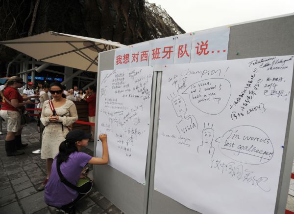 A girl writes words for the Spainish national soccer team outside the Spain Pavilion at the 2010 World Expo in Shanghai, east China, July 12, 2010. Spain won the football world cup for the first time in their history after defeating Holland in the final. 