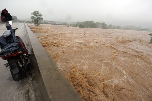 Flood waters run through a bridge in Chizhou city of East China&apos;s Anhui province, July 13, 2010. Torrential rain hit the city Tuesday, causing floods that cut off roads and triggered landslides. More than 50,000 residents were stranded in the flood waters while police and civil militia were making all-out efforts to evacuate them to safety. No casualties have been reported so far. [Xinhua]