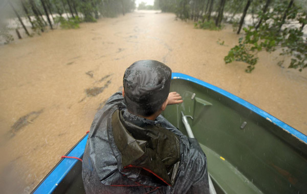 A man rides a boat on a road inundated by flood waters in Chizhou city of East China&apos;s Anhui province, July 13, 2010. [Xinhua]