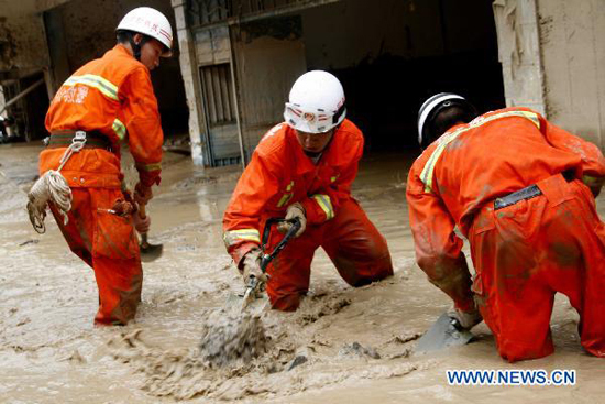 Firemen work on a flooded street in Xiaohe Town of Qiaojia County, southwest China's Yunnan Province, July 13, 2010. 13 people were killed and more than 30 others went missing after landslide and flood hit the town early Tuesday. As of noon, 43 people were also injured in the disaster.