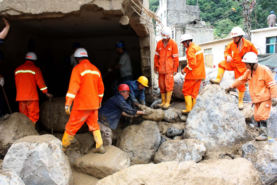 Firemen work on a flooded street in Xiaohe Town of Qiaojia County, southwest China's Yunnan Province, July 13, 2010. Four people were killed and 42 others went missing after landslide and flood hit the town early Tuesday. As of noon, 53 people were also injured in the disaster.