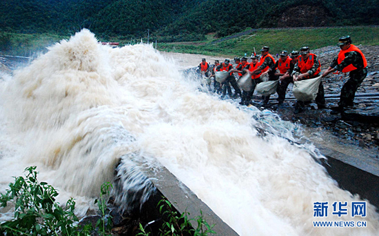 Armed police officers and soldiers struggle to strengthen the Meixi reservoir in Jiangxi Province on July 14, 2010. 