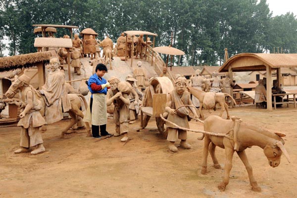 The clay sculpture from the famous Song Dynasty painting Along the River During the Qingming Festival is seen under construction in Tangshan, North China&apos;s Hebei province, July 15, 2010. The sculpture, 300-meter-long and 600 meter-wide, is 40% completed and scaled to two-thirds of the original scene and designed by Qin Shiping, a farmer-turned-entrepreneur from Tangshan city.[Xinhua]