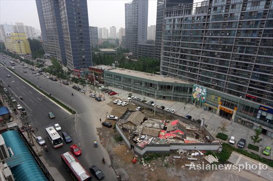 A 'nail house,' the last house in the area, stands in front of a tall building, blocking the road in Beijing's downtown area, July 14, 2010. 