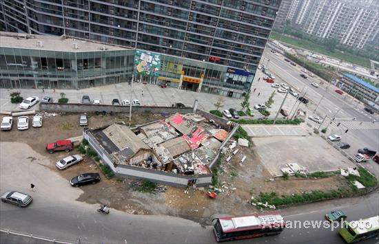 A bird&apos;s-eye view of a &apos;nail house&apos; standing in front of a tall building and blocking the road in Beijing&apos;s downtown area, July 14, 2010. [Asianewsphoto]