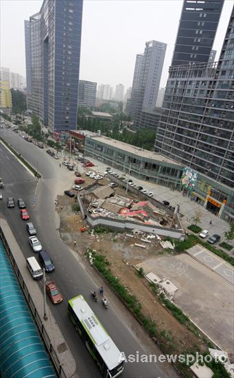 A bird&apos;s-eye view of a &apos;nail house&apos; standing in front of a tall building and blocking the road in Beijing&apos;s downtown area, July 14, 2010. [Asianewsphoto]