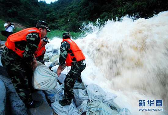 Armed police officers and soldiers struggle to strengthen the Meixi reservoir in Jiangxi Province on July 14, 2010. 