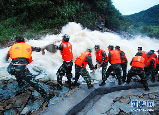 Armed police officers and soldiers struggle to strengthen the Meixi reservoir in Jiangxi Province on July 14, 2010. 