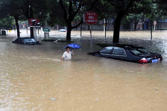 A man wades through a flooded street in Anqing, Anhui province, on July 13, 2010.