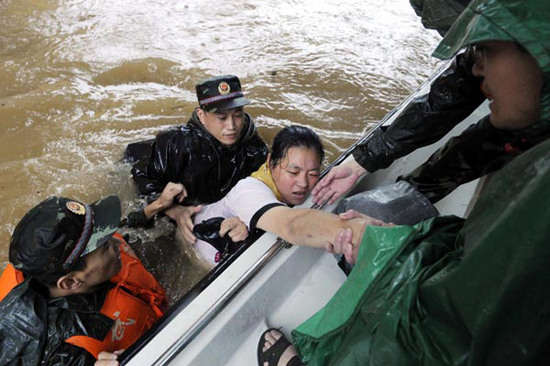 Rescuers help a flood victim get into a boat in Anqing, Anhui province, on July 13, 2010.