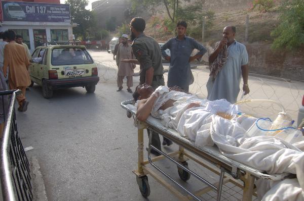 Security members send an injured to Peshawar&apos;s hospital in Pakistan, on July 15, 2010. Casualties in the suicide blast in Pakistan&apos;s northwest city of Mingora on Thursday have risen to 50, local media reported. [Saeed Ahmad/Xinhua]