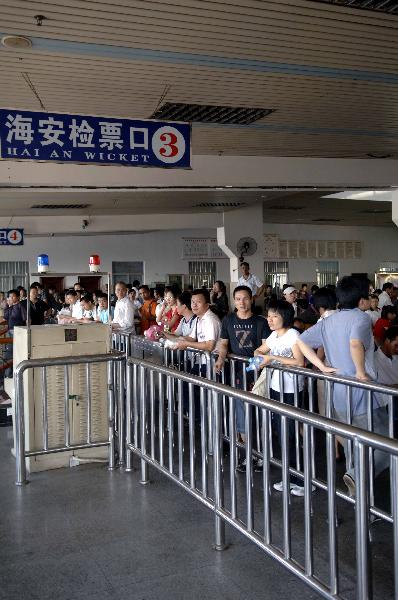 Passengers waits at a port in Haikou, capital of south China's Hainan Province, July 15, 2010. Local maritime affairs authorities ordered all ships to stay in port and suspended all shipping services across the Qiongzhou Strait because of the tropical storm Conson. [Xinhua]