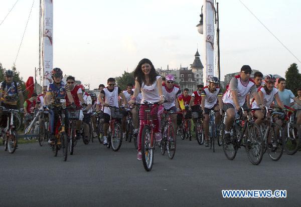 Miss Universe Romania 2010 Oana Paveluc (C, front) attends the campaign &apos;Red Bicycle&apos; in Bucharest, Romania, July 17, 2010. [Xinhua]