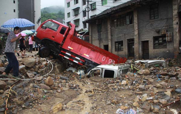 Vehicles are buried as floods lashed the Wanyuan city of Sichuan province, July 17, 2010. [Xinhua]