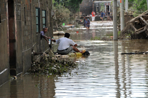  A man rides on a raft to bring water to villagers in Panyang, East China&apos;s Jiangxi province on July 17, 2010. [Xinhua]