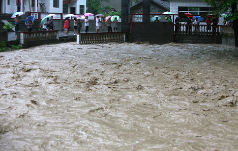 People watch a flood in the rain in Baokang, Central China&apos;s Hubei province on July 17, 2010. [Xinhua]