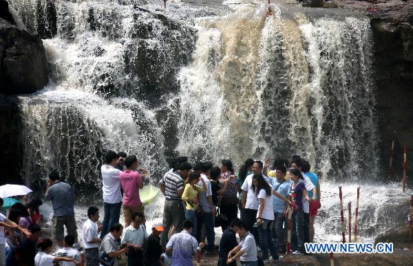 Tourists admire the spectacular torrents of the Hukou Waterfall on the Yellow River, resulting from upriver precipitation, near Jixian County, northern China's Shanxi Province, July 17, 2010. [Xue Jun/Xinhua] 