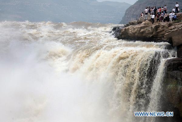 Tourists admire the spectacular torrents of the Hukou Waterfall on the Yellow River, resulting from upriver precipitation, near Jixian County, northern China's Shanxi Province, July 17, 2010. [Xue Jun/Xinhua]