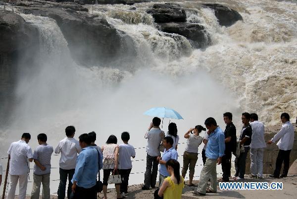 Tourists admire the spectacular torrents of the Hukou Waterfall on the Yellow River, resulting from upriver precipitation, near Jixian County, northern China's Shanxi Province, July 17, 2010. [Xue Jun/Xinhua] 