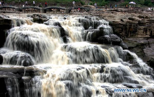 Tourists admire the spectacular torrents of the Hukou Waterfall on the Yellow River, resulting from upriver precipitation, near Jixian County, northern China's Shanxi Province, July 17, 2010. [Xue Jun/Xinhua] 