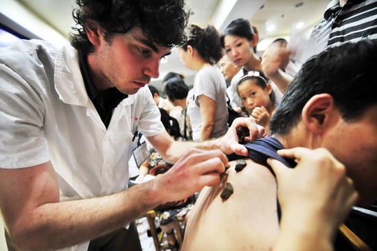  An Austrilian medical intern works in Zhejiang Chinese Medicine Hospital, helping patients to get medical plasters on the very first day of &apos;toufu&apos; in Hangzhou city, east China&apos;s Zhejiang province on July 19, 2010.