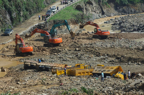 Cranes work to dig out trucks hit by a landslide in Chengkou county, Chongqing municipality, July 20, 2010. The sudden disaster occurred Monday night, blocking Luojiang River and forming a barrier lake that threatened the security of nearby villages. More than 10,000 villagers have been excavated to safety. [Xinhua] 