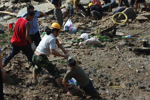 A worker pulls a fellow worker who fell in the mud at the scene of the disaster in Chengkou county, Chongqing municipality, July 20, 2010. [Xinhua] 