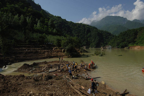 Workers manage to dispel mud rocks to allow floodwater to move after a landslide in Chengkou county, Chongqing municipality, July 20, 2010. [Xinhua] 