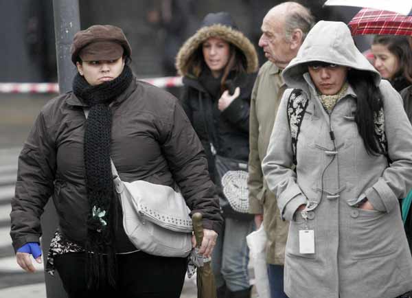 People in thick garments walk on a street in Buenos Aires, capital of Argentina, July 19, 2010. At least 28 people had died, 16 from hypothermia, as a polar cold wave swept across Argentina during the past week, authorities said Monday. [Xinhua]