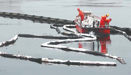 Workers in Dalian, Liaoning province, start on Sunday to clean up the crude oil that gushed into the sea after an oil pipe exploded at the coastal city's Xingang Harbor. [China Daily] 