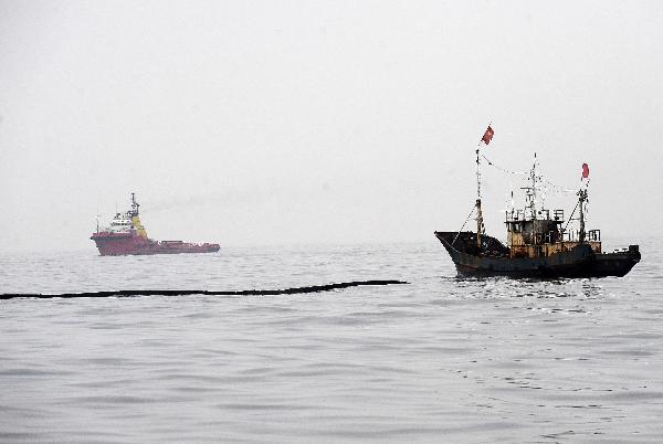 A vessel (R) lays protective booms around the area affected by oil leakage in Dalian, a coastal city in northeast China&apos;s Liaoning Province on July 19, 2010. More than 500 fishing boats were set off Monday to clean up the crude oil that gushed into the sea after an oil pipe exploded at Dalian Xingang Harbor. Another 4 patrol boats kept monitoring the diffusion of oil and cleaning work, while laying out more protective boom.