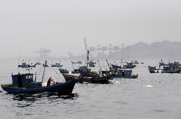 Boats carry out cleaning work in the area affected by oil spill in Dalian, a coastal city in northeast China&apos;s Liaoning Province on July 19, 2010. More than 500 fishing boats were set off Monday to clean up the crude oil that gushed into the sea after an oil pipe exploded at Dalian Xingang Harbor. Another 4 patrol boats kept monitoring the diffusion of oil and cleaning work, while laying out more protective boom. [Xinhua]