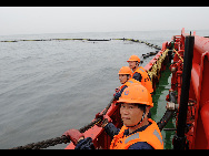 Workers clean up the leaking oil at the polluted sea area in Dalian, northeast China's Liaoning Province, July 19, 2010. [Xinhua]