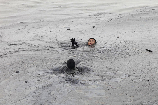 A pair of works fall in to the sea when trying to fix an underwater pump on a pipeline which exploded last week pouring 1,500 tonnes of crude into the sea in Dalian, northeast China&apos;s Liaoning Province. [163.com]