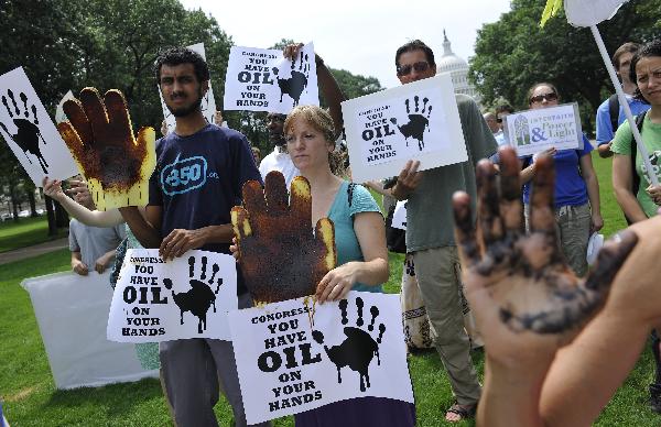 Activists hold placards during a protest to mark the three-month anniversary of the Deepwater Horizon oil rig explosion before the Capitol Hill in Washington D.C., capital of the United States, July 20, 2010. British Prime Minister David Cameron, on his first official visit to Washington, on Tuesday tried to appease the massive rage at BP company, which was blamed for the responsibility for the Gulf of Mexico oil disaster. [Zhang Jun/Xinhua] 