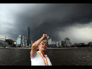 A reporter take photos of the clouds covering Guangzhou City in south China's Guangdong Province, July 21, 2010 [Xinhua]