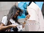 A woman trys to open her umbrella in Hong Kong , south China, July 21, 2010.  [Xinhua]