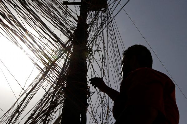  Abbas Ahmed navigates a network of generator wires during a power outage in Baghdad, Iraq on June 25, 2010.[yeeyan.org]