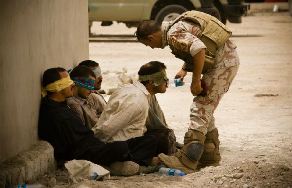 An Iraqi soldier from 2nd Division gives water to detainees after returning to their base from a morning mission on June 5, 2010 in Mosul, Iraq. [yeeyan.org]