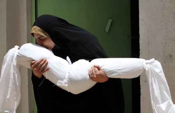 A woman kisses the shrouded body of her four-year-old niece, Zainab, who was killed in a Baghdad bombing, as the family prepares for her burial in the Shi&apos;ite city of Najaf, 160 km (100 mi) south of Baghdad, Iraq, Monday, June 21, 2010. The child was killed along with her entire family - mother, father, and sister - on Sunday, when suicide bombers attacked a a crowded Baghdad commercial district.[yeeyan.org]