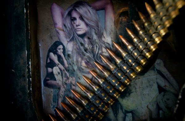 A belt of bullets lies across photos of women adorning the armor of a Stryker vehicle on June 11, 2010 north of Jalaulah, Diyala Province, Iraq. [yeeyan.org]