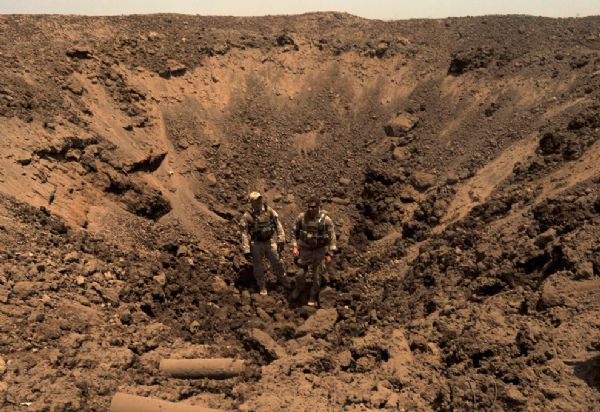 U.S. Sailors assigned to Navy Explosive Ordnance Disposal Mobile Unit 2, Company 2-2 survey a crater left behind after detonating seized ordnance at a secure Iraqi demolition range in Diyala province, Iraq, June 17, 2010. The joint demolition operations with Soldiers assigned to the 5th Iraqi Army Bomb Disposal Company disposed of more than 100 pounds of ordnance seized by Iraqi Security Forces.[yeeyan.org]