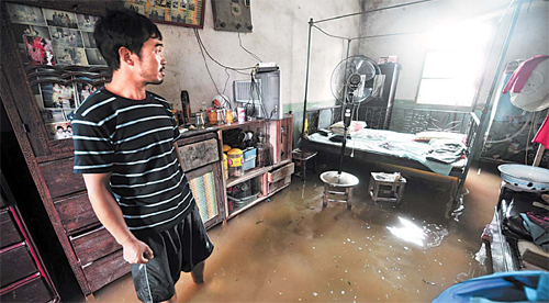 A villager stands in his flooded house in Xintan township of Honghu city, Central China's Hubei province on Wednesday. The water level in the township's Shatao Lake has risen to a record high of 25.9 meters due to days of torrential rain. [Xinhua]