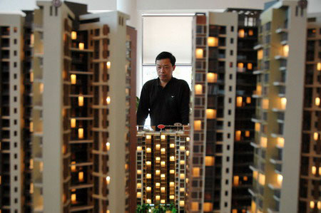A home buyer looks at a real estate sand table model in Beijing.