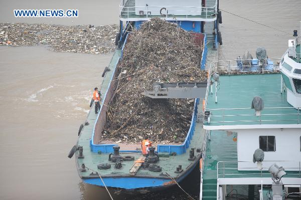 A cleaning boat collects floating garbage near Three Gorges Dam in central China&apos;s Hubei Province, July 21. Several boats are working around the clock to keep the large amounts of floating garbage brought by the flood of Yangtze River from obstructing the flow through the dam. [Xinhua]