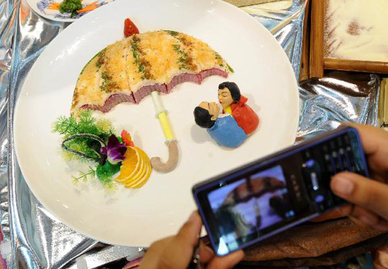 A visitor takes photo of a dish displayed at a food cultural festival held in Nanjing, capital of east China's Jiangsu Province, July 21, 2010. The festival which opened here on Thursday included a series of activities, such as exhibition of food culture, cultural exchange of old-branded restaurants and painting and calligraphy creation on food, etc. [Xinhua photo]