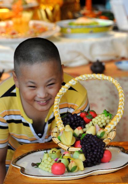 A boy watches some wheaten food in shape of fruits displayed at a food cultural festival held in Nanjing, capital of east China's Jiangsu Province, July 21, 2010. The festival which opened here on Thursday includes a series of activities, such as exhibition of food culture, cultural exchange of old-branded restaurants and painting and calligraphy creation on food, etc. [Xinhua photo]