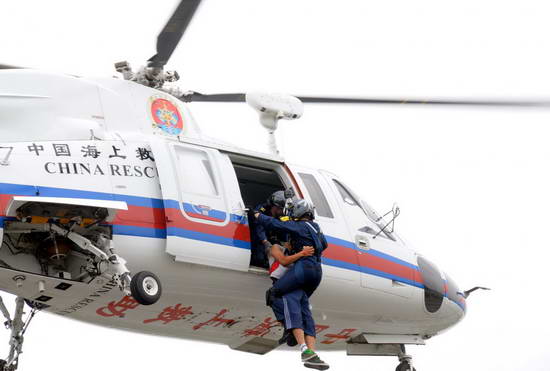 A rescue worker and a person injured in a simulated bridge collapse are lifted into a helicopter during a rescue drill on the Shenyang-Dalian highway in Northeast China&apos;s Liaoning Province, July 22, 2010. [Xinhua]