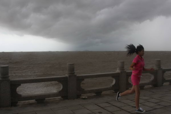 A woman runs on a road as dark clouds gain in the sky in Zhuhai, South China&apos;s Guangdong province, after Typhoon Chanthu lands on the province Thursday, July 22, 2010. Chanthu, the third typhoon of the season, made landfall at the coastal area of Wuchuan City, South China&apos;s Guangdong Province, at around 1:45 pm Thursday, with winds near its center at 126 km per hour. [Photo/Xinhua]